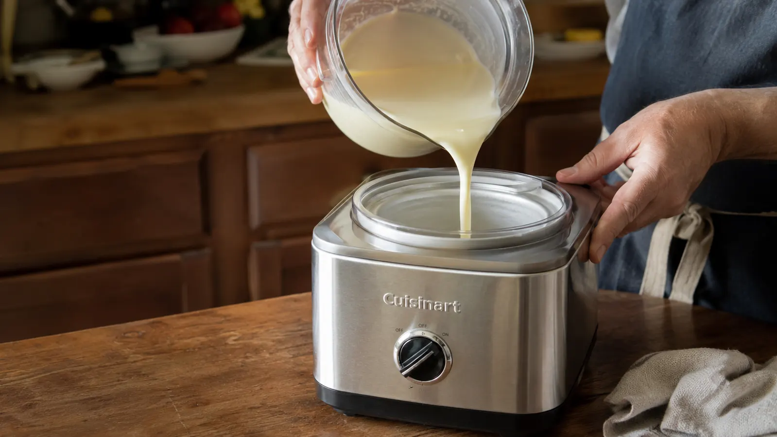 Hand pouring a cream mixture into the Cuisinart ICE-21P1 ice cream maker's frozen bowl