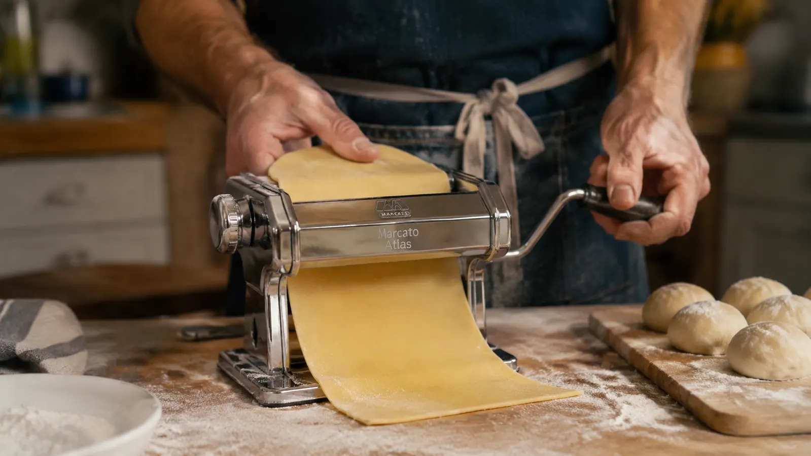 Hand cranking the Marcato Atlas pasta machine to roll a sheet of dough thin