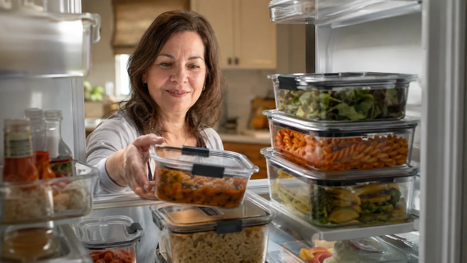 An organized refrigerator shelf filled with stacked clear Rubbermaid Brilliance food storage containers